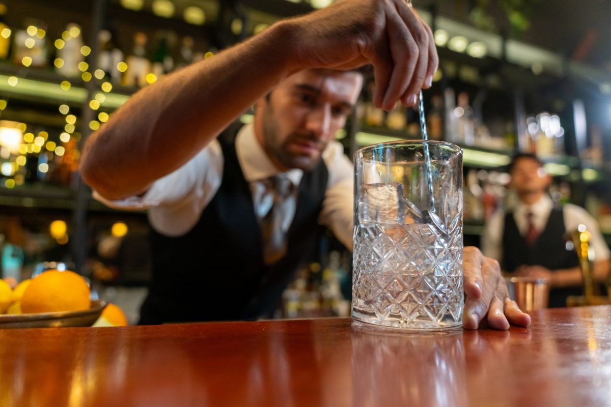 A professional bartender meticulously stirring a craft cocktail in a crystal mixing glass at an upscale Austin lounge, highlighting the high-end nightlife experiences available to guests staying with Walker Luxury Vacation Rentals.